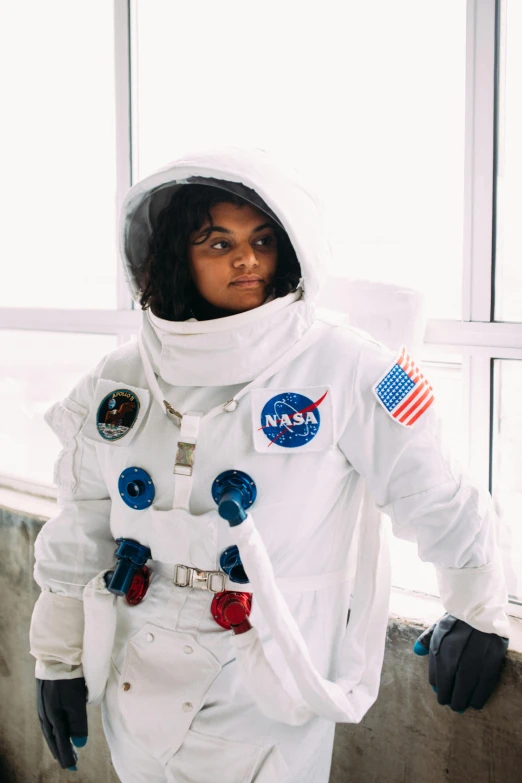 a woman in an astronaut suit standing in front of a window, photo of a black woman, - 9, modelling, spacecore