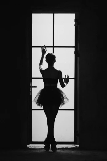 a black and white photo of a woman in a tutu, inspired by Lillian Bassman, tumblr, about to enter doorframe, silhouettes, standing with her back to us, waving