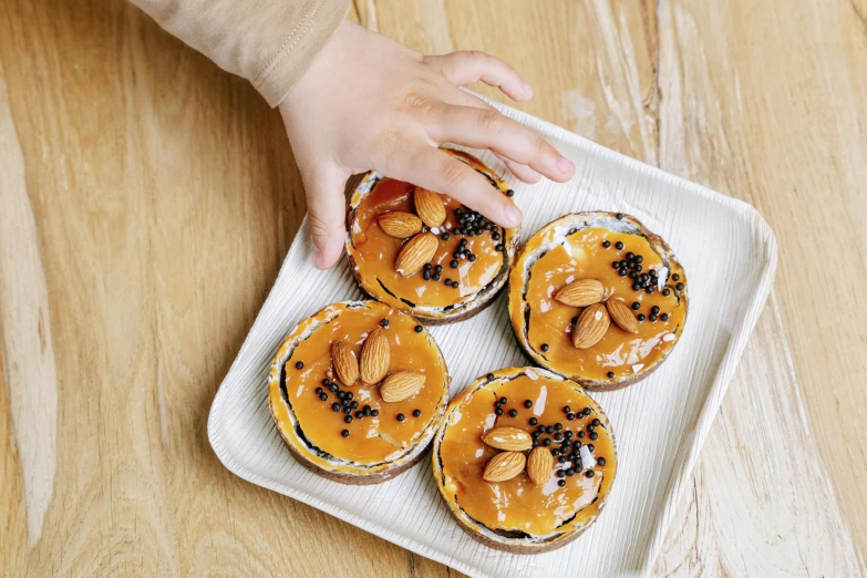 a close up of a plate of food on a table, a picture, by Emma Andijewska, unsplash, hurufiyya, eating cakes, 4yr old, sleek hands, caramel