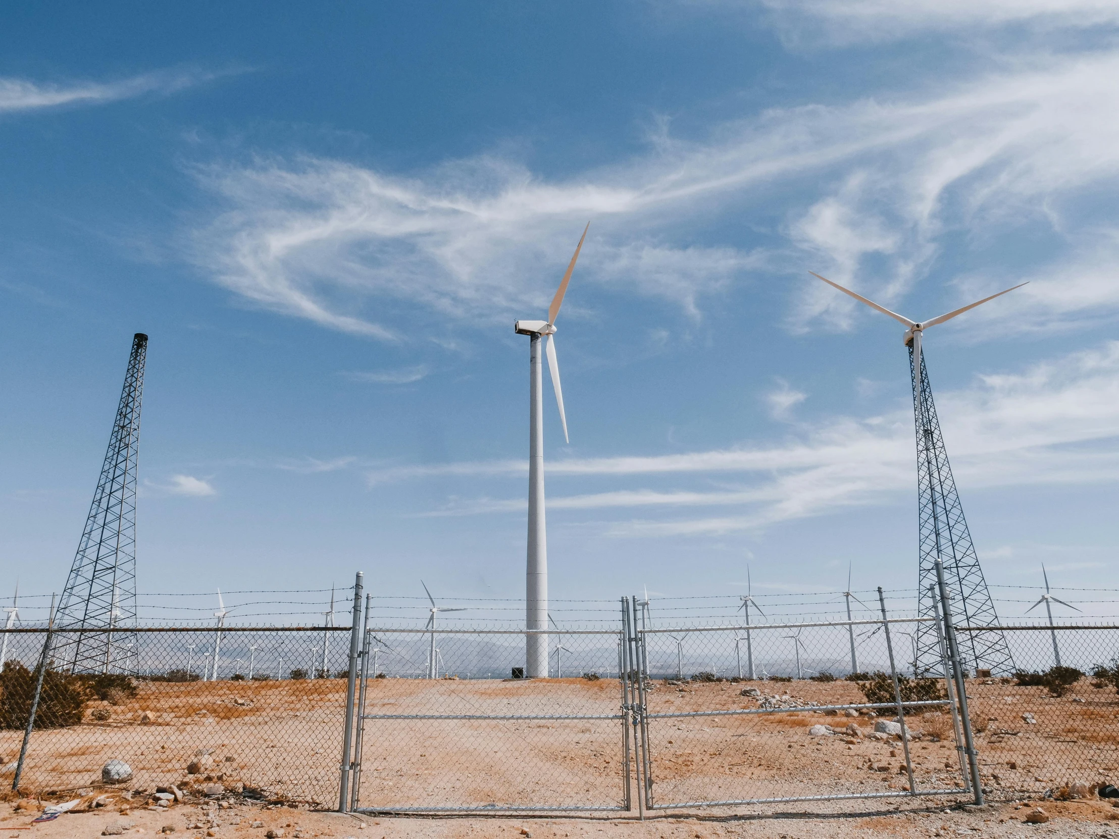 a group of wind turbines sitting on top of a dirt field, by Carey Morris, pexels contest winner, panoramic shot, fan favorite, electrical wires, whealan