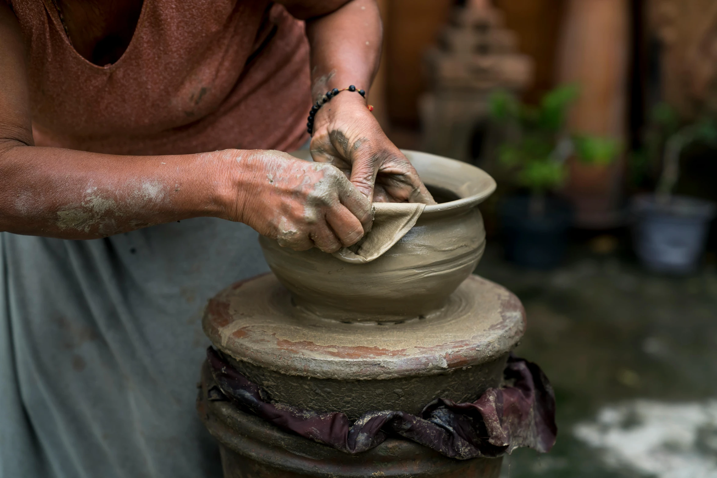 a woman is making a pot out of clay, a portrait, inspired by Hendrik Gerritsz Pot, pexels contest winner, bali, thumbnail, half turned around, medium closeup