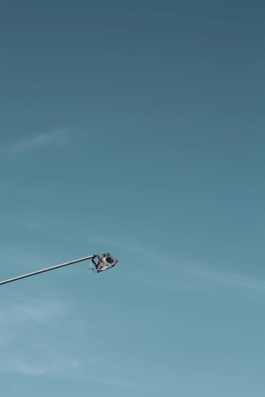 a street light in front of a blue sky, by Andries Stock, unsplash, postminimalism, sitting in a crane, camera low, helicopters, tiny person watching