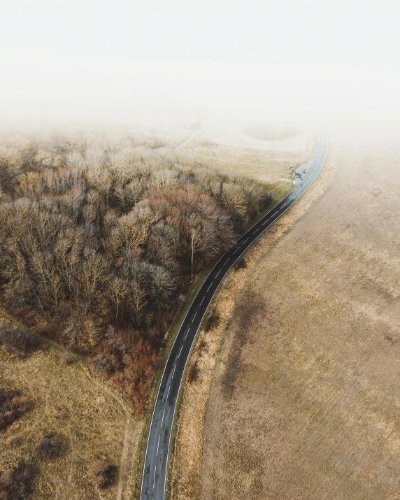 an aerial view of a road in the middle of a field, by Adam Marczyński, slightly foggy, low quality photo