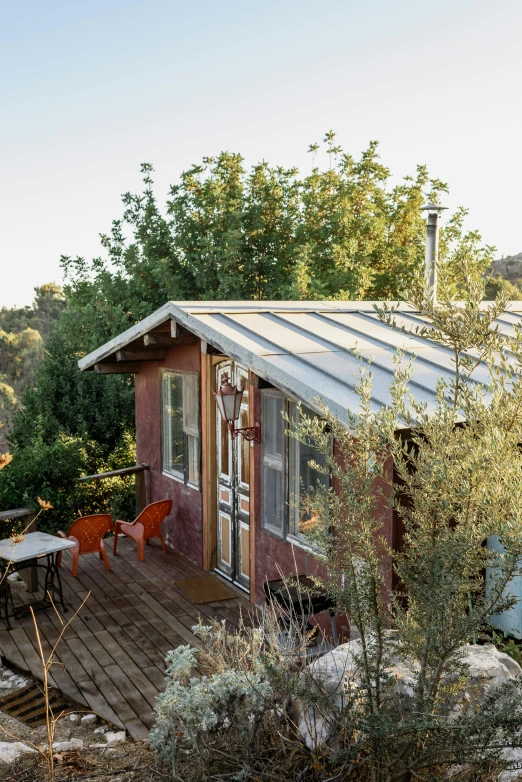 a house sitting on top of a lush green hillside, by Jessie Algie, plants and patio, galvalume metal roofing, a cozy, studio