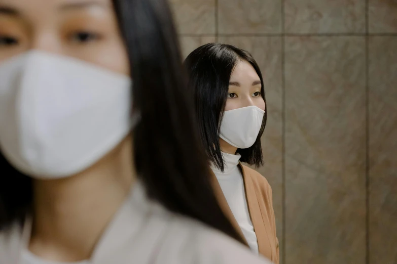 a woman standing in front of a mirror wearing a face mask, inspired by Kanō Naizen, trending on pexels, hyperrealism, two girls, promotional image, sustainable materials, wearing white clothes