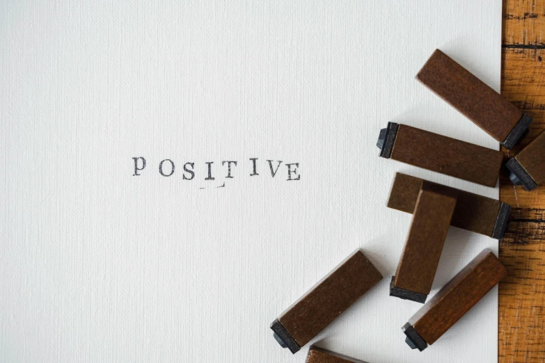 a piece of paper sitting on top of a wooden table, a picture, positive vibes, brown, set against a white background, stamp