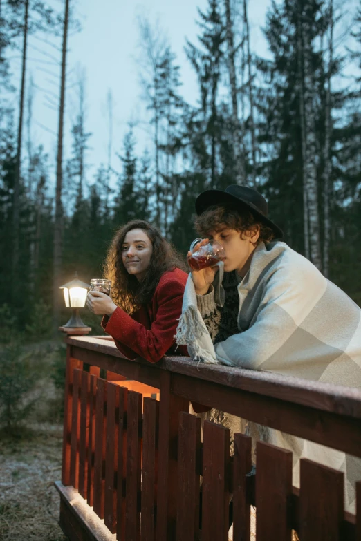 a group of people sitting on top of a wooden bridge, by Jaakko Mattila, pexels contest winner, romanticism, holding a candle holder, romantic couple, cottagecore hippie, drinking