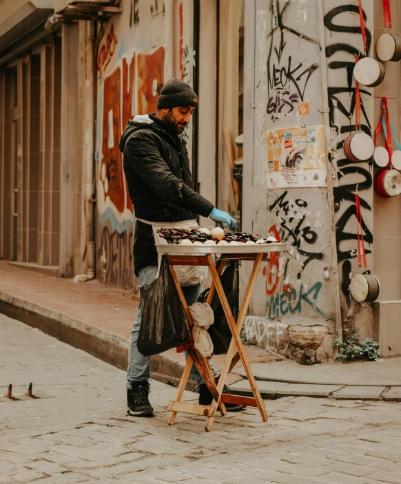a man standing next to a table on a sidewalk, pexels contest winner, street art, cooking it up, instrument, thumbnail, cyberpunk market