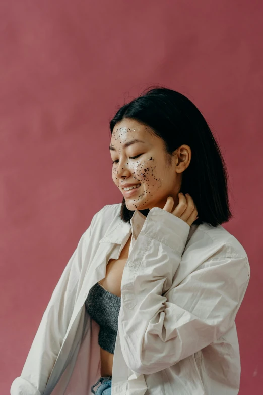 a woman standing in front of a pink wall, a black and white photo, trending on pexels, mingei, burn scar left cheek, star trek asian woman, white freckles, character is covered in liquid