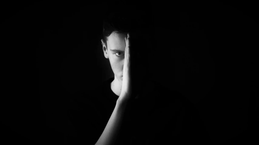 a black and white photo of a man covering his face, a black and white photo, aestheticism, posing in dramatic lighting, icon black and white, vitalik buterin, a portrait of @hypnos_onc