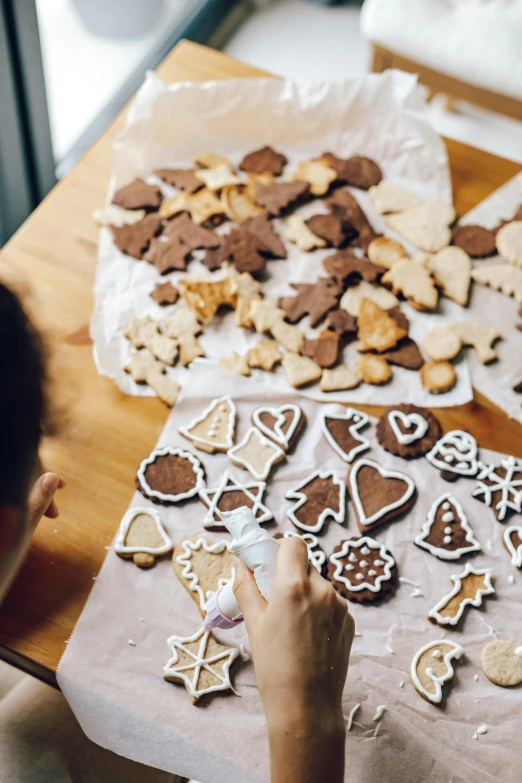 a person that is making some cookies on a table, by Julia Pishtar, trending on pexels, process art, decorated ornaments, diecut, brown, full of light