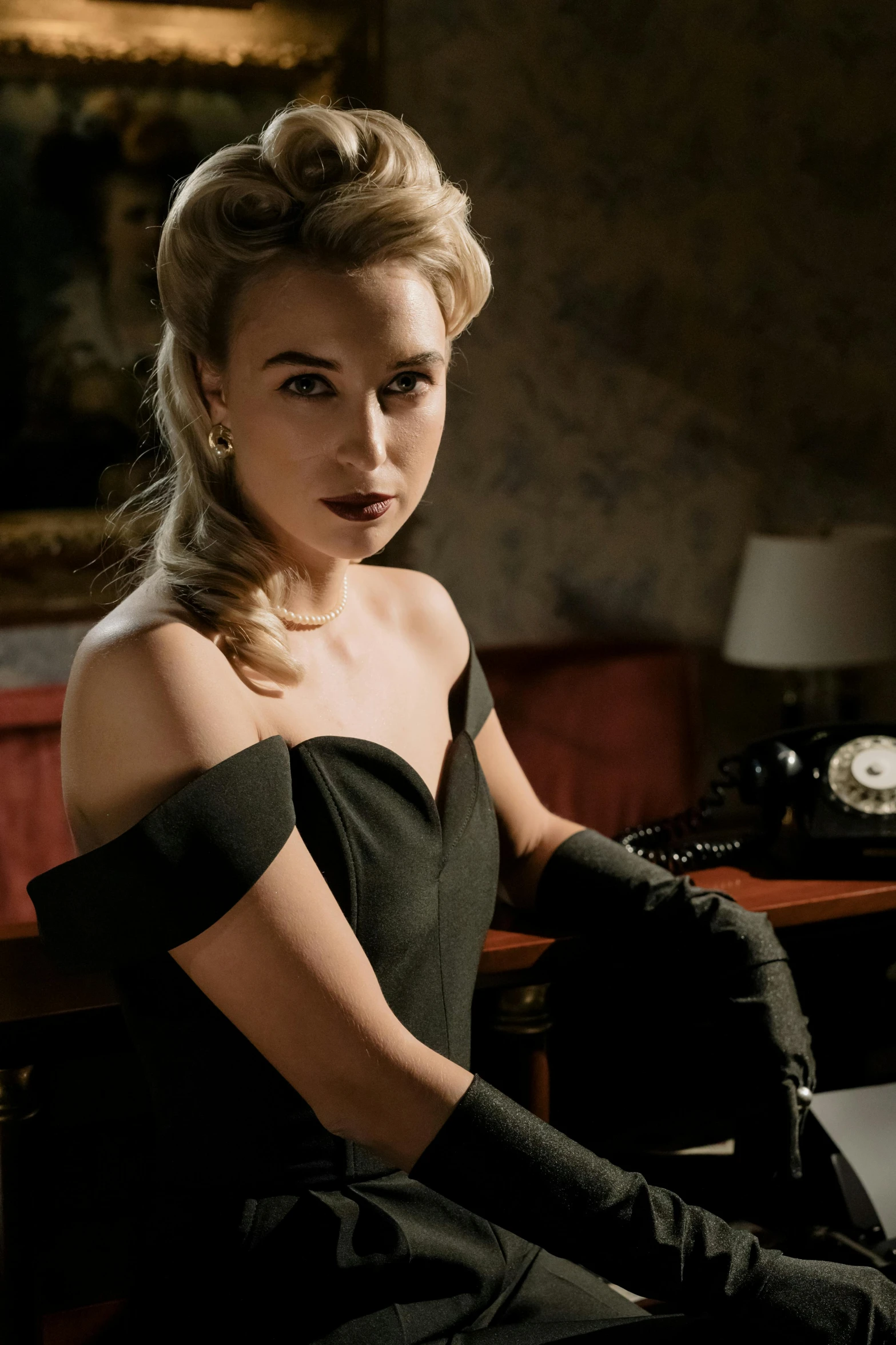 a woman in a black dress sitting on a desk, inspired by Evaline Ness, trending on cg society, photo of margot robbie, [ theatrical ], lilly collins, black gloves