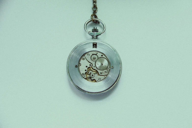 a close up of a pocket watch on a chain, by Lubin Baugin, unsplash, minimalism, made from mechanical parts, silver and muted colors, programming, on a pale background