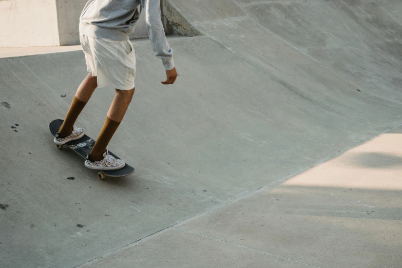 a man riding a skateboard up the side of a ramp, unsplash contest winner, hyperrealism, tan skin a tee shirt and shorts, gray concrete, ignant, pearly flagstones