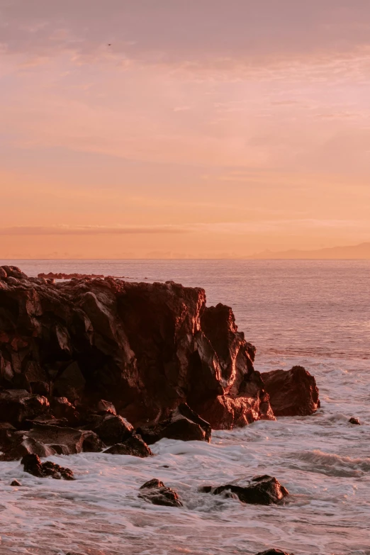 a man standing on top of a rock next to the ocean, inspired by Elsa Bleda, pexels contest winner, romanticism, brown and pink color scheme, maui, today\'s featured photograph 4k, red and orange glow