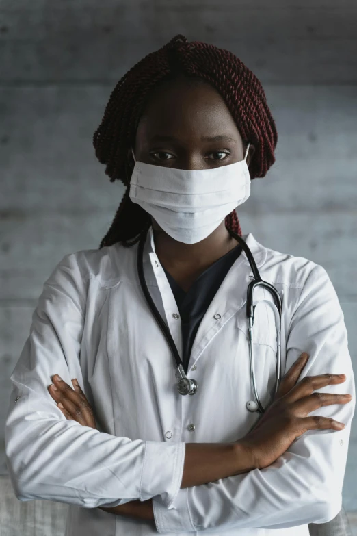 a woman wearing a mask and standing with her arms crossed, a picture, inspired by Dr. Atl, trending on pexels, stethoscope, african, on a gray background, gauze