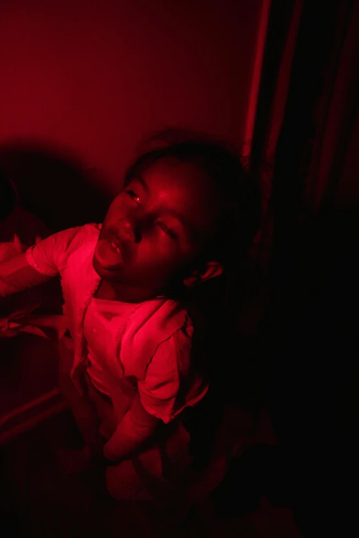 a small child sitting in front of a red light, an album cover, inspired by Carrie Mae Weems, pexels contest winner, inside haunted house, red lighting on their faces, ( ( dark skin ) ), excitement