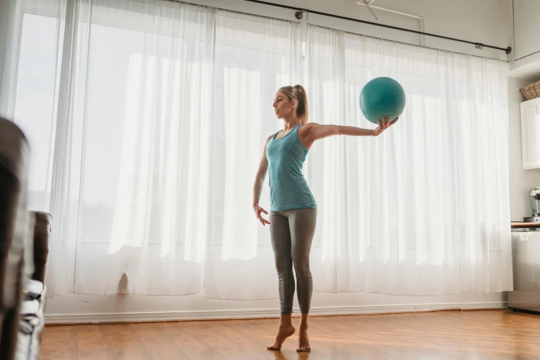 a woman holding a medicine ball in a living room, arabesque, origin jumpworks, with backdrop of natural light, closed limbo room, twirls