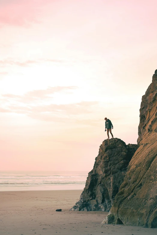 a person standing on top of a rock on a beach, coastal cliffs, zac retz, gaze down, overlooking