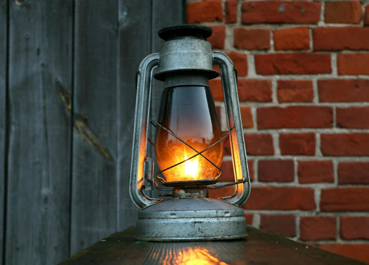 a lantern sitting on top of a table next to a brick wall, an album cover, pixabay, carbide lamp, petrol energy, octane realphoto, light inside the hut