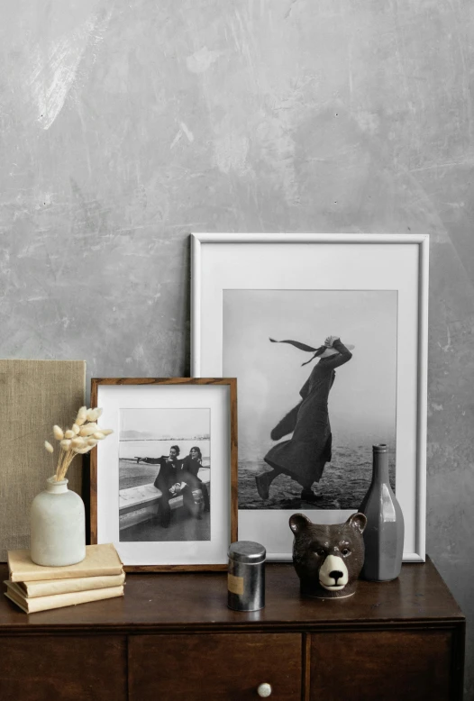 a white vase sitting on top of a wooden dresser, poster art, inspired by Carl Gustaf Pilo, pexels contest winner, square pictureframes, weathered concrete, model posing, cute photograph