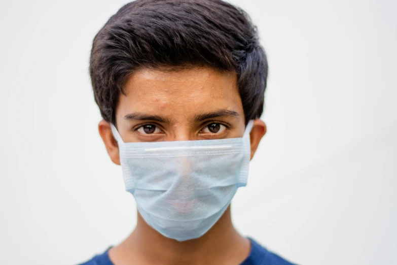 a close up of a person wearing a face mask, by Daniel Lieske, shutterstock, hurufiyya, boy with neutral face, medicine, on a pale background, around 20 yo