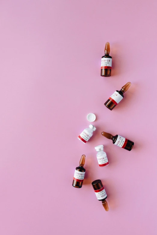 several bottles of essential oils on a pink background, by Julia Pishtar, white and red color scheme, thumbnail, mini model, clinical