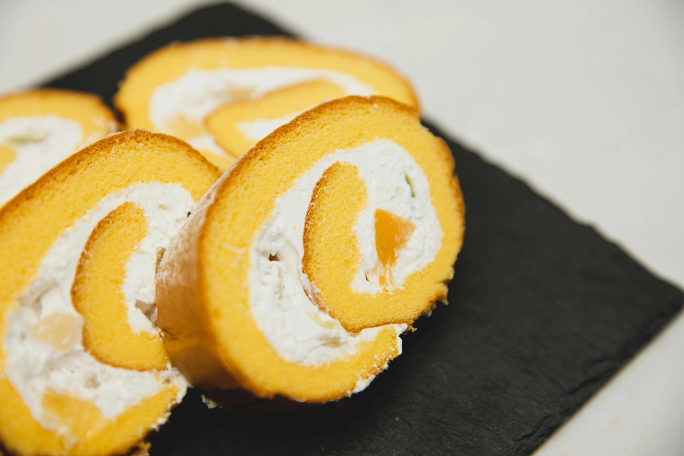 a close up of a piece of food on a plate, orange and white, scrolls, product image, cakes