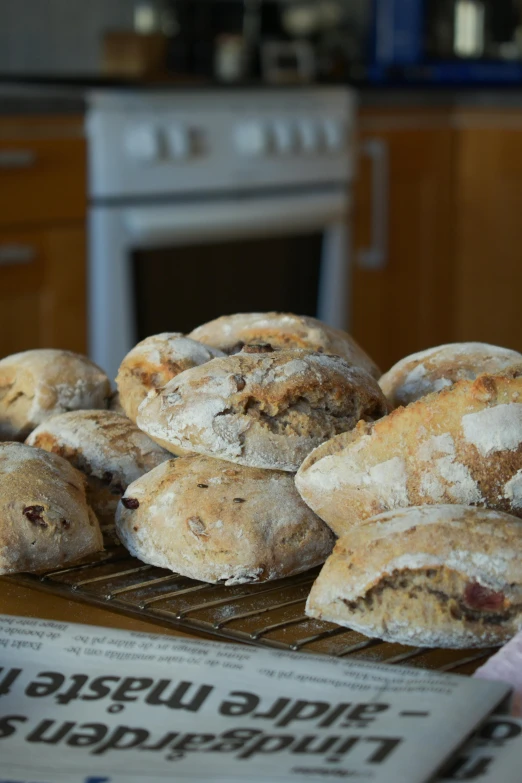 a bunch of bread sitting on top of a cooling rack, inspired by Normand Baker, cornwall, back towards camera, ready to eat, large eddies