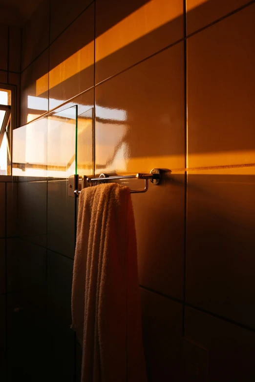 a towel hanging on a rack in a bathroom, by Peter Churcher, flickr, bauhaus, sunset at golden hour, shadowy, angle view, showers