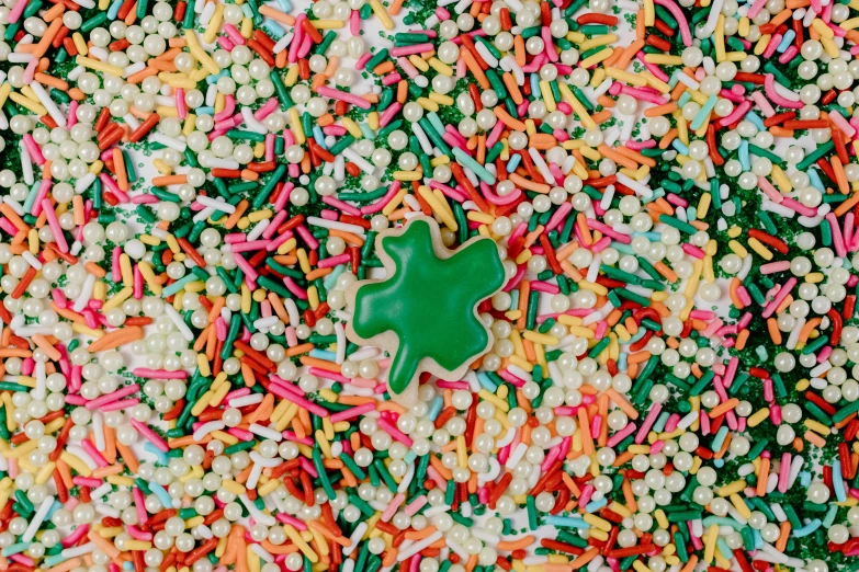 a green shamrock sitting on top of a pile of sprinkles, a jigsaw puzzle, glazed, vanilla, top-down shot, starburst