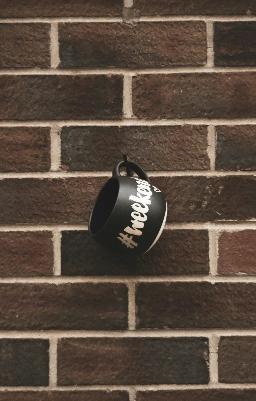 a coffee cup hanging on a brick wall, band merchandise, hashtags, theneedledrop, profile image