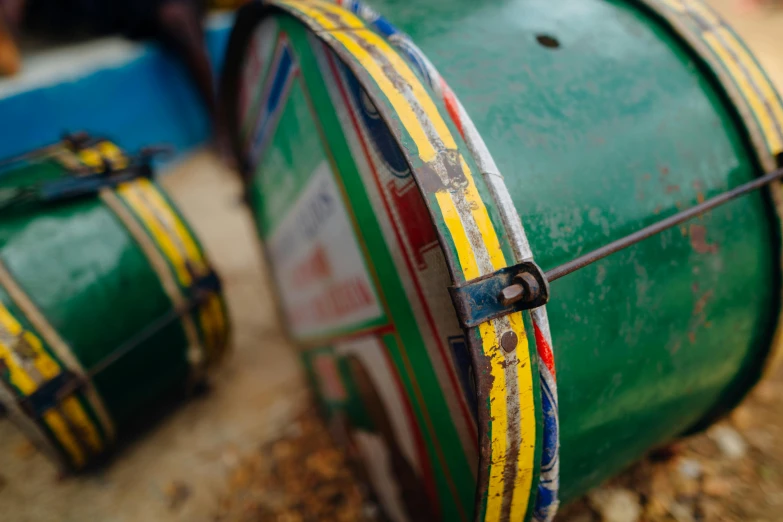 a green drum sitting on top of a pile of rocks, unsplash, yellow and blue ribbons, barrels, detail shot, multicoloured