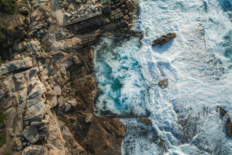 a large body of water next to a rocky shore, pexels contest winner, birdseye view, sydney, pools of water, battered