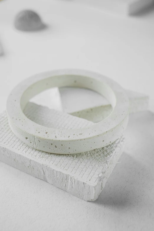 a white ring sitting on top of a piece of paper, concrete art, detailed product shot, 130mm, modeled, speckled