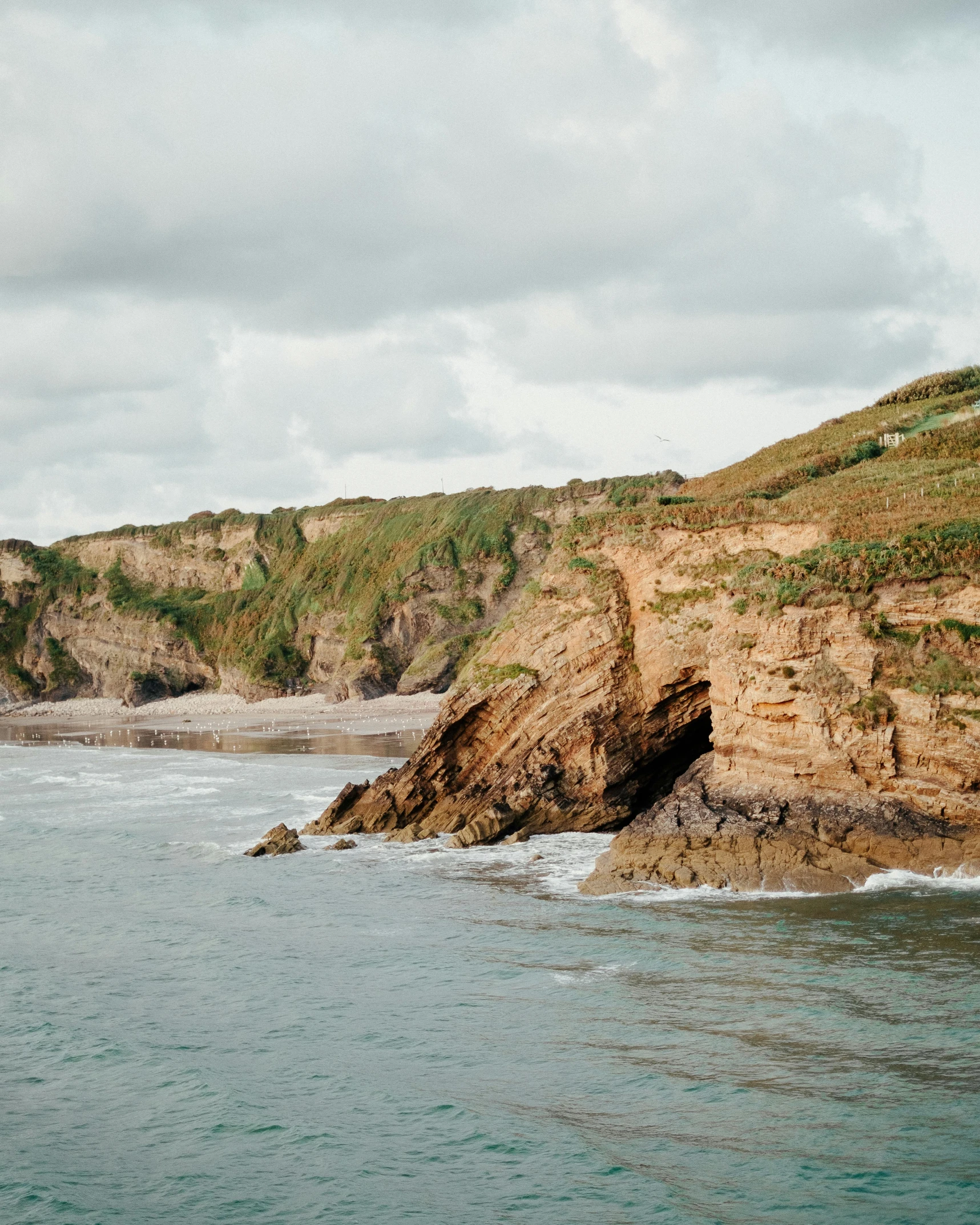 a large body of water next to a cliff, by Rachel Reckitt, pexels contest winner, omaha beach, farming, slightly tanned, thumbnail