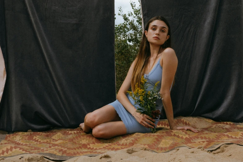 a woman sitting on the ground holding a bunch of flowers, inspired by Elsa Bleda, unsplash contest winner, magic realism, blue dress, wearing a tank top and shorts, portrait sophie mudd, film promotional still