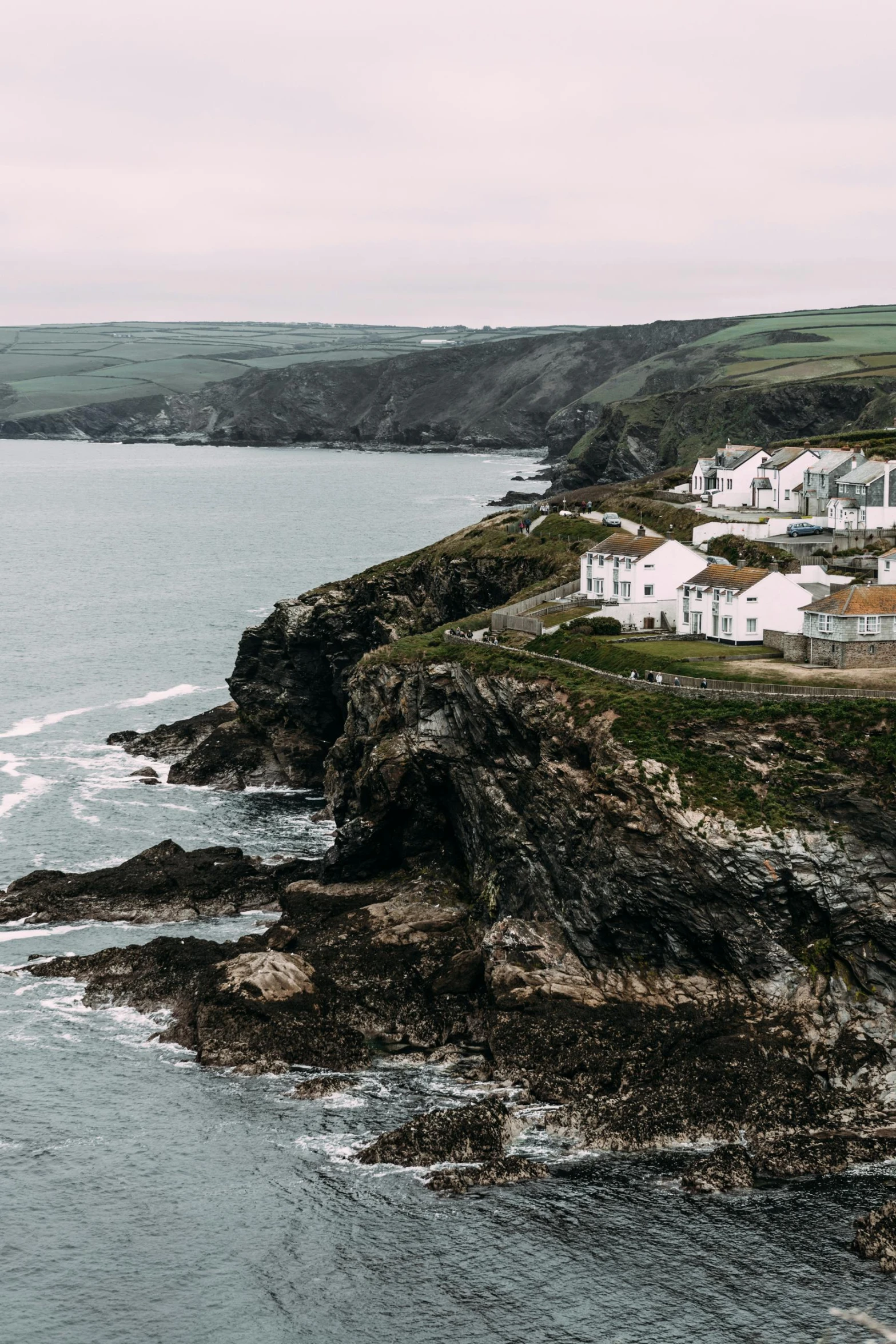 a white house sitting on top of a cliff next to the ocean, by Rory McEwen, pexels contest winner, renaissance, several cottages, unsplash 4k, dean cornwall, overcast