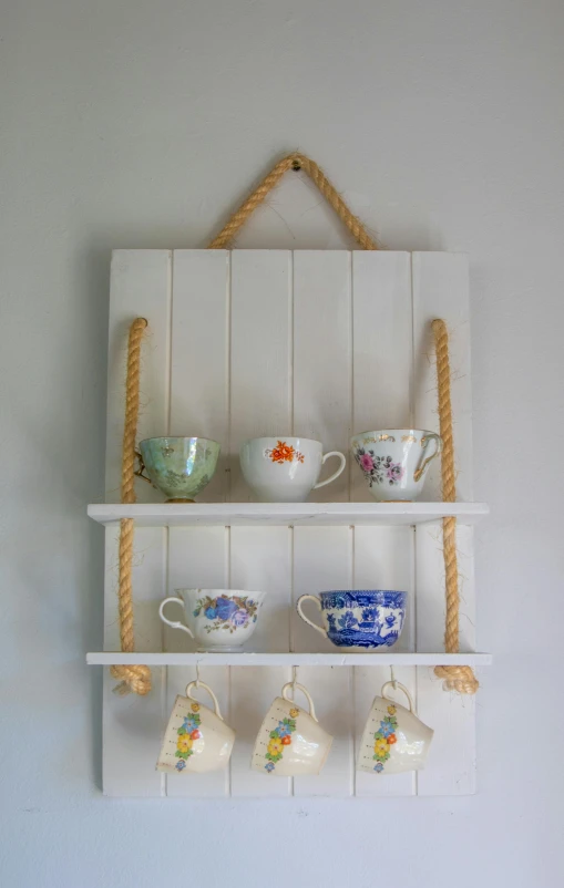 a shelf that has cups and mugs on it, a portrait, inspired by William Twigg-Smith, unsplash, hanging rope, medium wide front shot, fully decorated, coastal