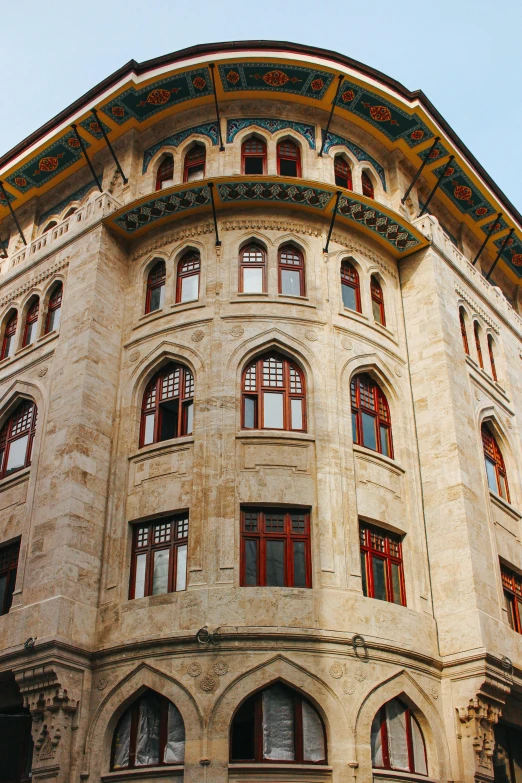 a very tall building with lots of windows, inspired by Osman Hamdi Bey, pexels contest winner, art nouveau, stone facade, ocher details, rounded roof, early 2 0 th century