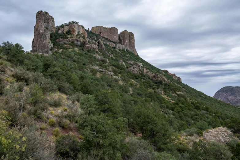 a mountain that has some rocks on top of it, by Arnie Swekel, unsplash, art nouveau, new mexico, slight overcast weather, steep cliffs, battlements