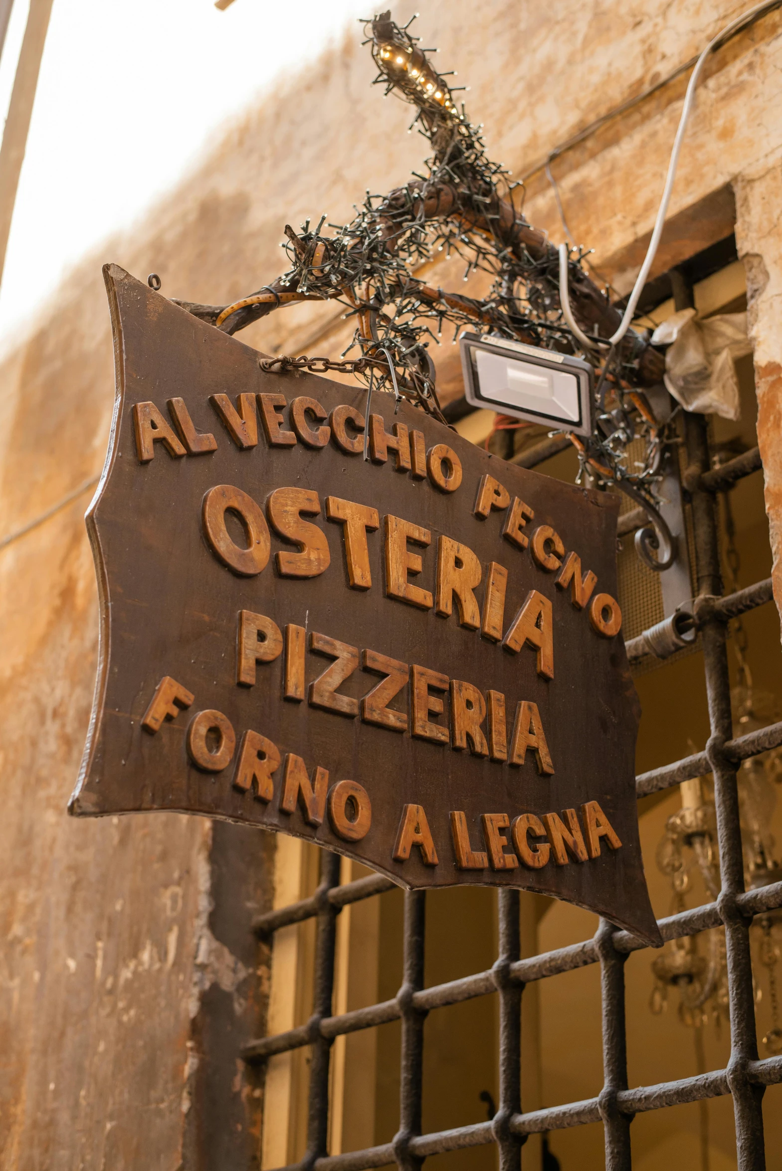 a sign hanging from the side of a building, by Romano Vio, rustic setting, sharing a pizza, sienna, exterior photo