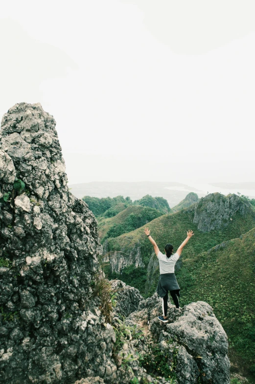 a person standing on top of a mountain with their arms in the air, philippines, limestone, looking out, instagram post