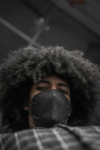 a close up of a person wearing a face mask, by Lily Delissa Joseph, pexels contest winner, afrofuturism, long afro hair, tear gas, grey, panel of black