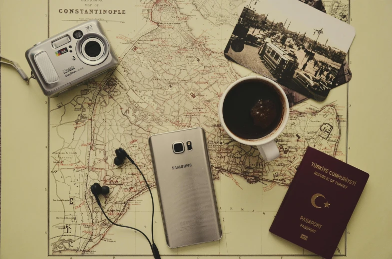 a cell phone sitting on top of a map next to a cup of coffee, a picture, pexels contest winner, passport, istanbul, old sepia photography, modelling
