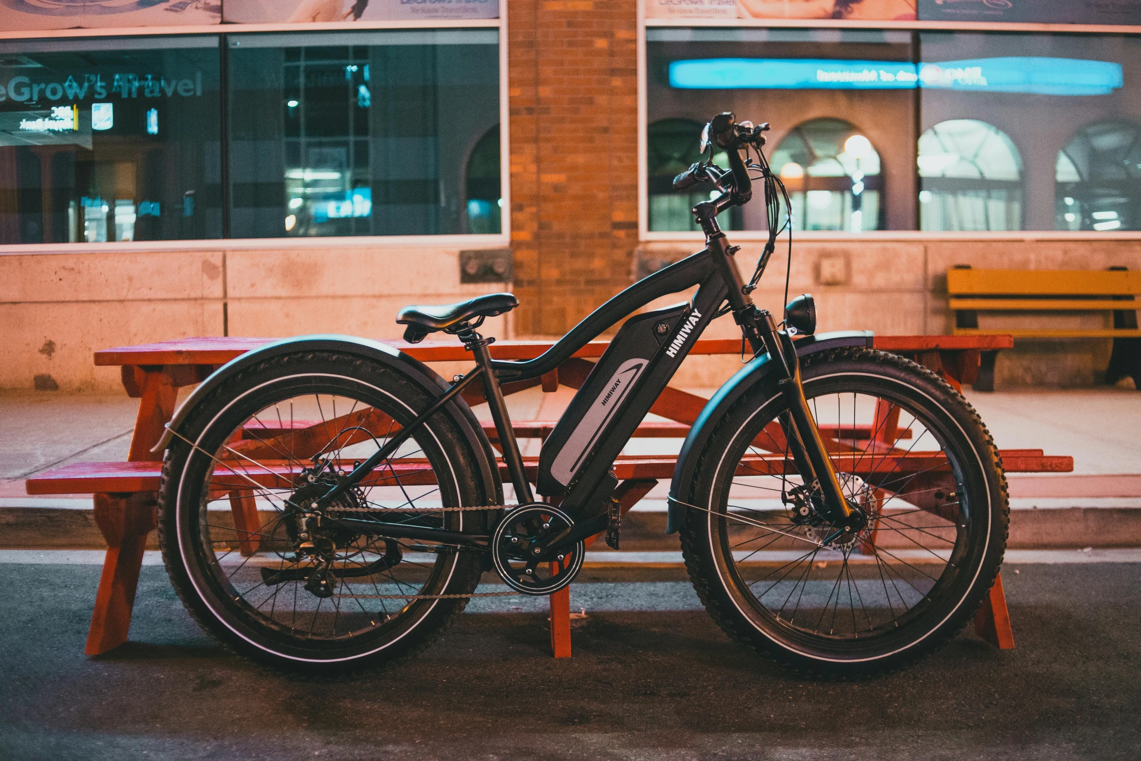 a bicycle parked next to a bench in front of a building, profile image, in the evening