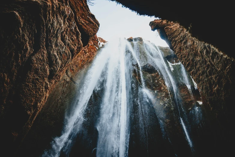 a person standing in front of a waterfall, unsplash contest winner, hurufiyya, view from below, tears running down, ancient caves, thumbnail