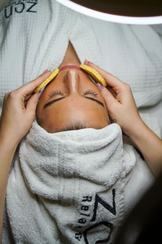 a close up of a person with a towel on their head, laying down, facial, thumbnail, manicured