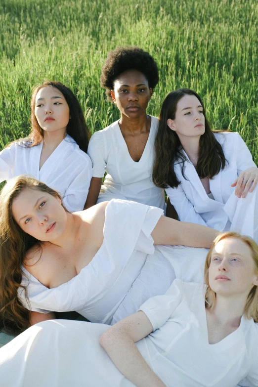 a group of women sitting on top of a lush green field, an album cover, inspired by Vanessa Beecroft, unsplash, renaissance, white uniform, natural complexion, moonlight, skincare