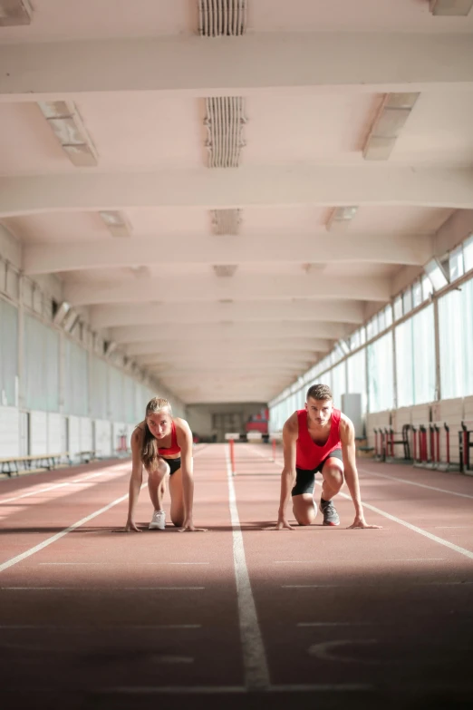 a couple of men standing next to each other on a track, by Jessie Algie, shutterstock, renaissance, indoor, red sport clothing, medium distance, university